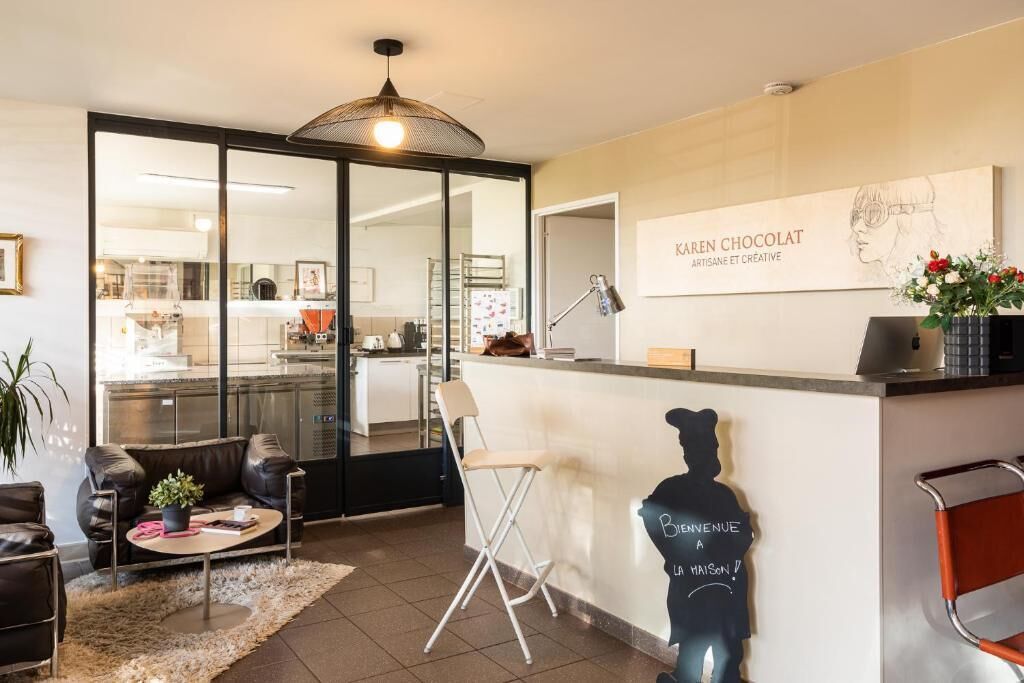 A modern interior with a bar area, seating, and a kitchen visible through glass doors.
