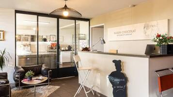 A modern interior with a bar area, seating, and a kitchen visible through glass doors.
