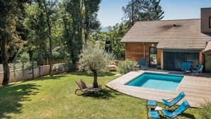 Un patio trasero con piscina, sillas de descanso y una terraza de madera.