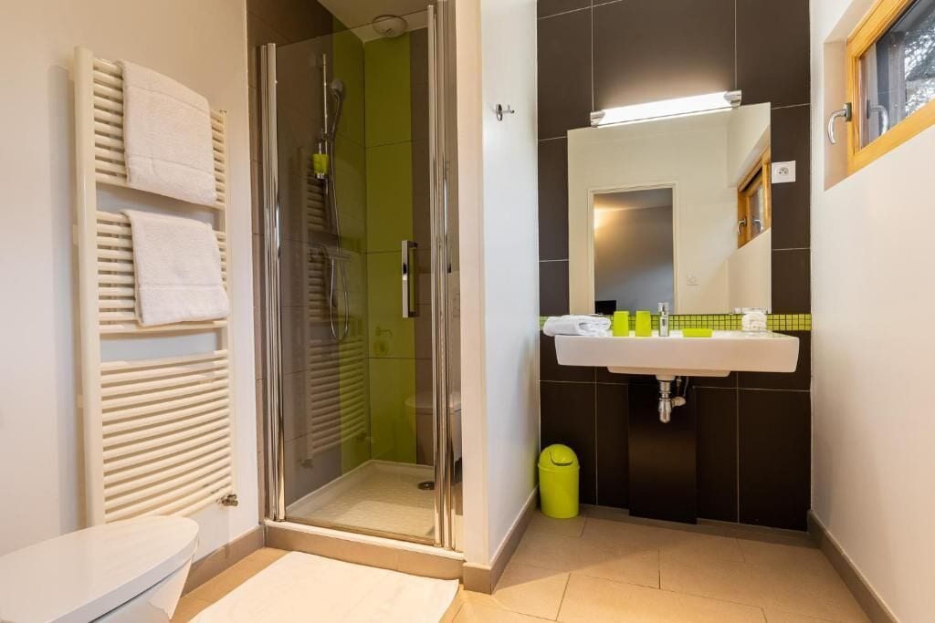 A bathroom with a glass shower enclosure, a white sink with a mirror, and a toilet.