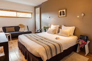 A bedroom with a large bed, a bedside table, a chair, a window, and a wall-mounted light fixture. - La Maison de Karen Chocolat (Limonest)