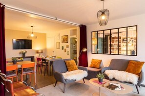 Una sala de estar moderna con un sofá, sillones, una zona de comedor y un televisor.