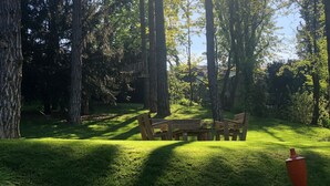 Un parque con un banco de madera y un bote de basura rojo.