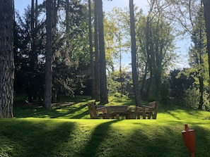A park with a wooden bench and a red trash bin.