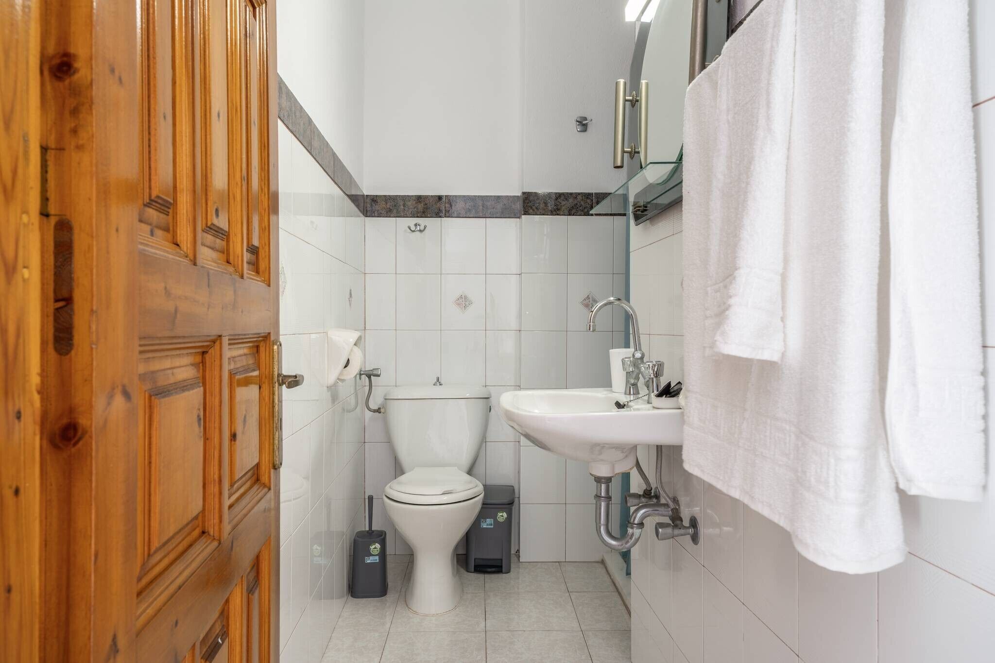 A bathroom with a toilet, sink, and wooden door.