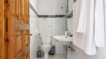 A bathroom with a toilet, sink, and wooden door.
