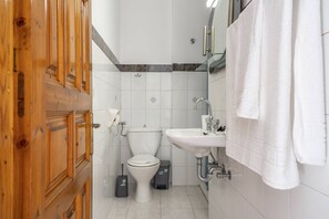A bathroom with a toilet, sink, and wooden door. - Anastasia's 1 Apartment with Private Balcony and Sea View (Skala)