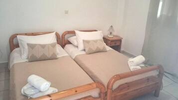 A double bed with wooden headboards, a bedside table with a lamp, and a rolled towel on the floor.