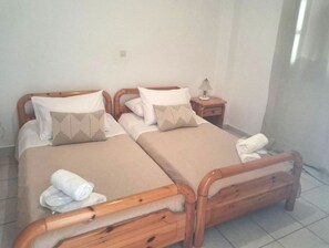 A double bed with wooden headboards, a bedside table with a lamp, and a rolled towel on the floor. - Anastasia's 1 Apartment with Private Balcony and Sea View (Skala)