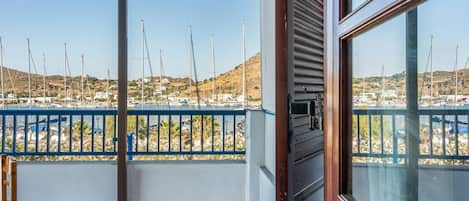 A balcony with a view of a marina, a tiled floor, and a wooden door frame.