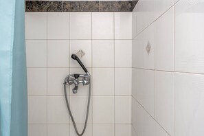 Ducha con cabezal de ducha manual y manguera flexible, montada en una pared de azulejos con diseño en esquina.