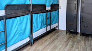 Ein Schlafsaalzimmer mit Etagenbetten, einem Kleiderschrank und einer Decke mit freiliegenden Rohren.
