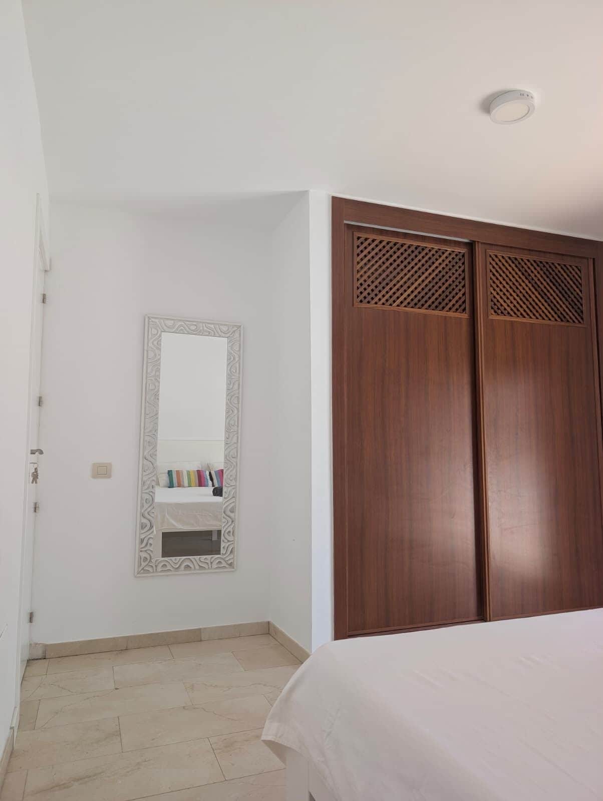 Una camera da letto con un letto, un armadio, uno specchio e una porta.