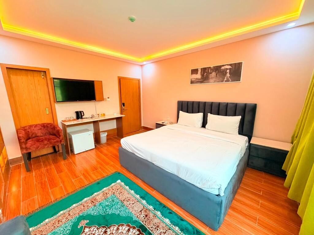 Une chambre à coucher avec un lit, un bureau, une chaise, une télévision et un tableau accroché au mur.