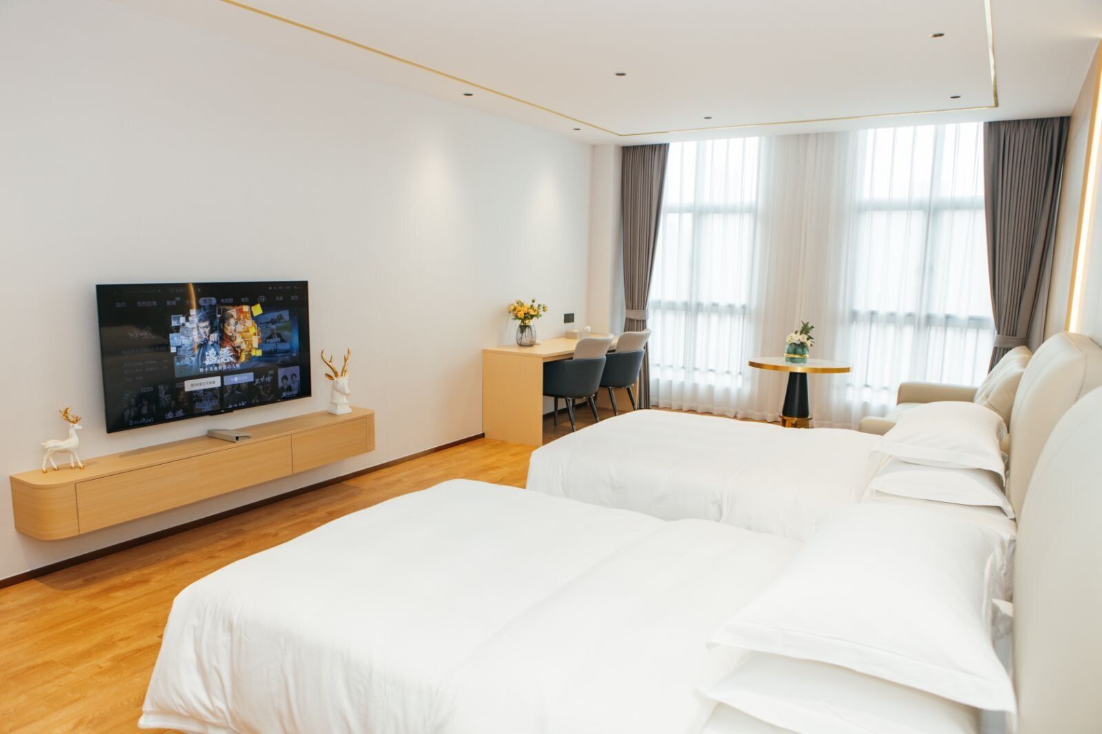 A hotel room with a bed, a desk, a chair, a TV, and a window with curtains.