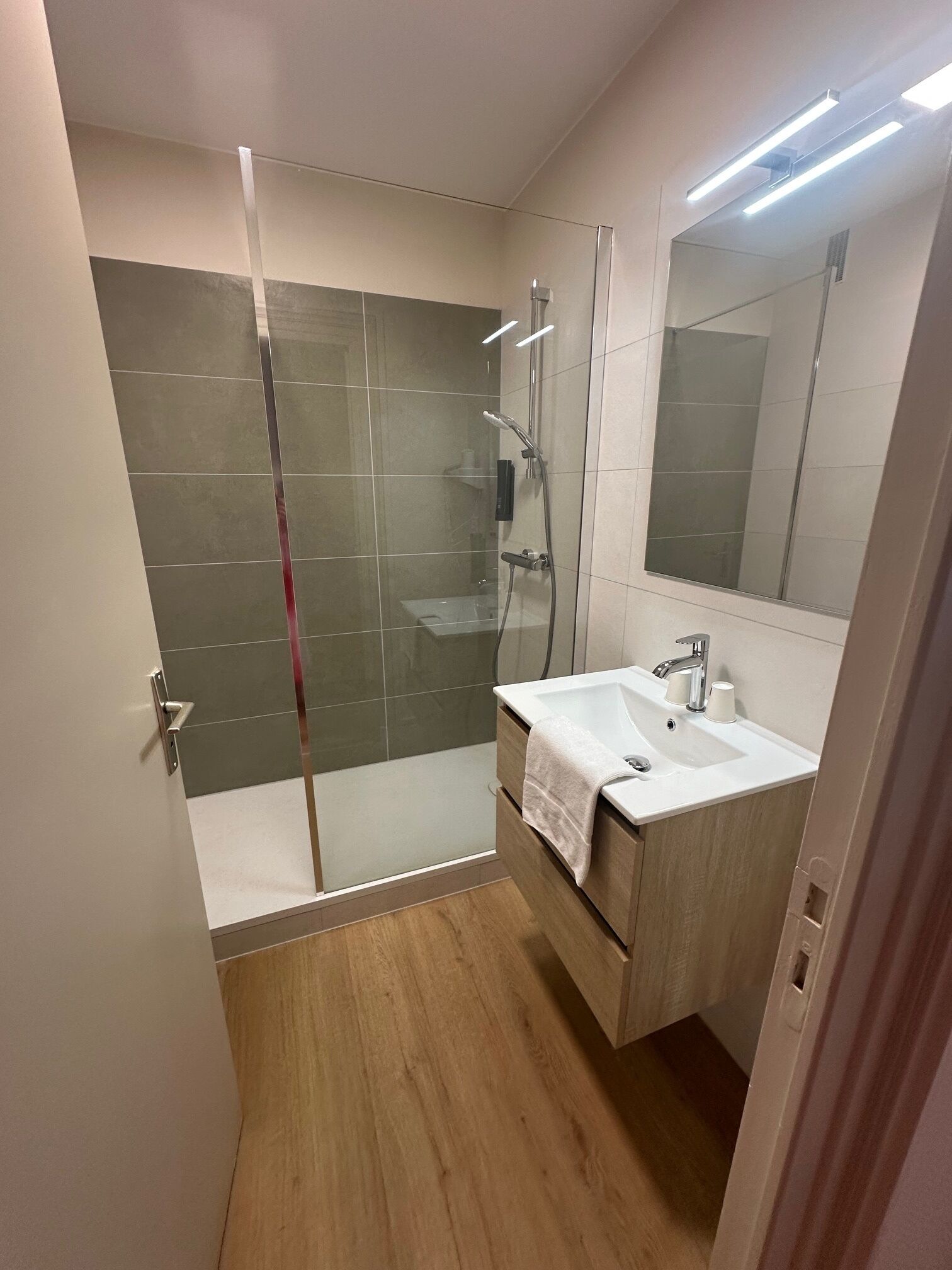Un baño moderno con cabina de ducha de vidrio, tocador con lavamanos y espejo.