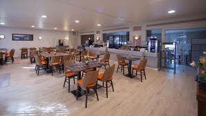 Un comedor amplio con varias mesas y sillas, una barra de cocina y vistas al exterior.
