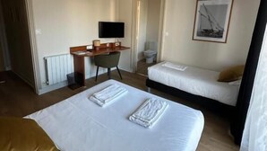 Habitación de hotel con dos camas, un escritorio, una silla, un televisor y un cuadro en la pared.