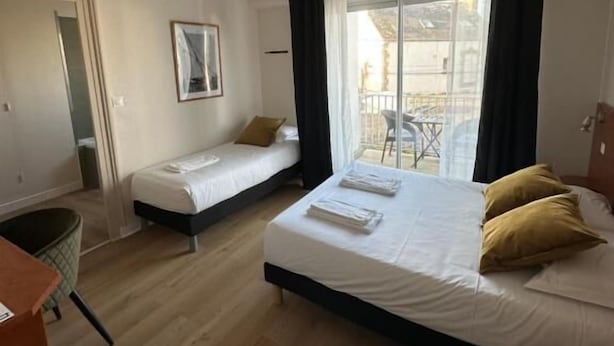 Habitación de hotel con una cama grande, una cama más pequeña, un escritorio y una ventana con cortinas.