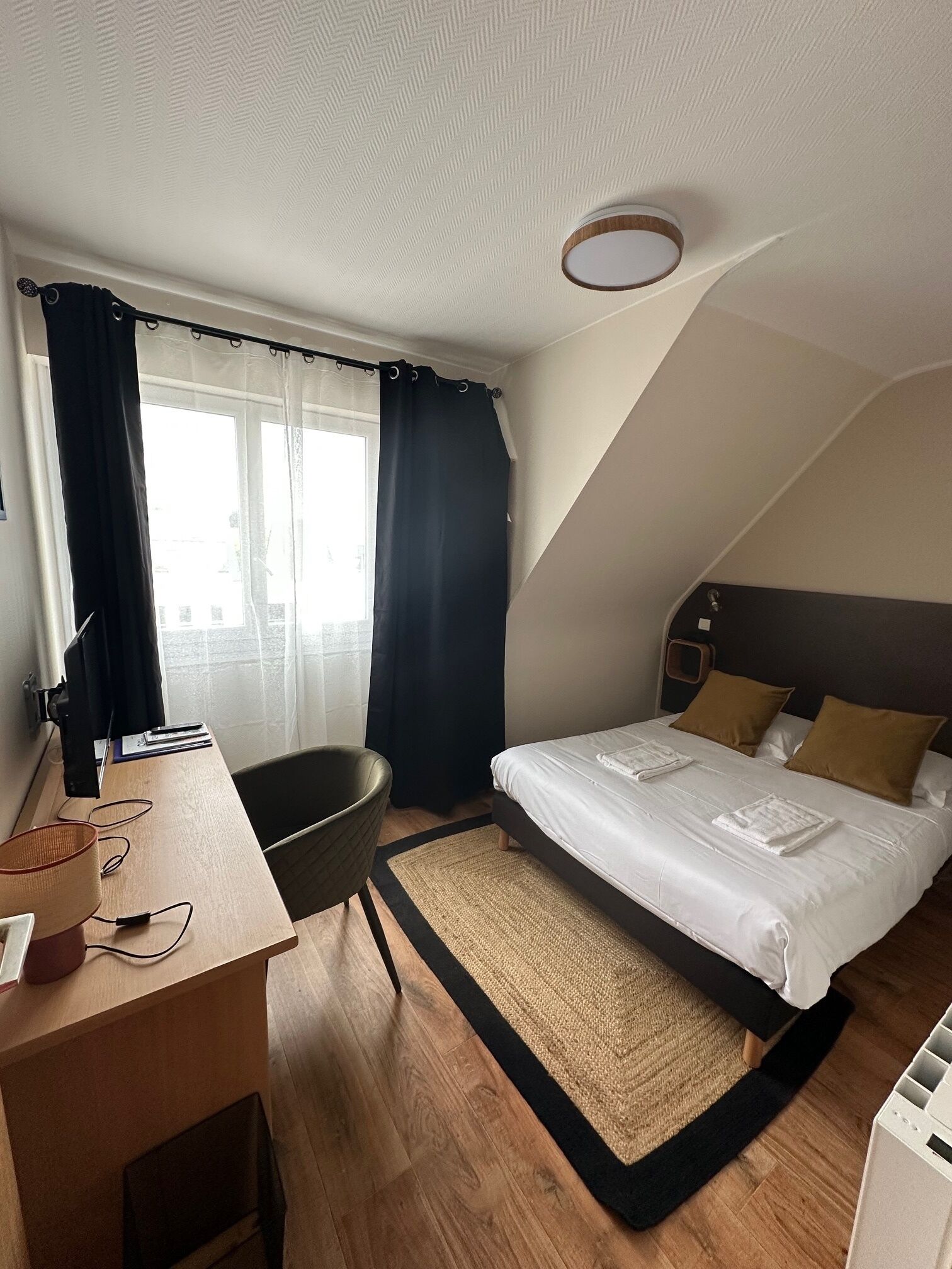 Een hotelkamer met een bed, bureau, stoel en uitzicht.
