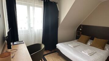 Een hotelkamer met een bed, bureau, stoel en uitzicht.