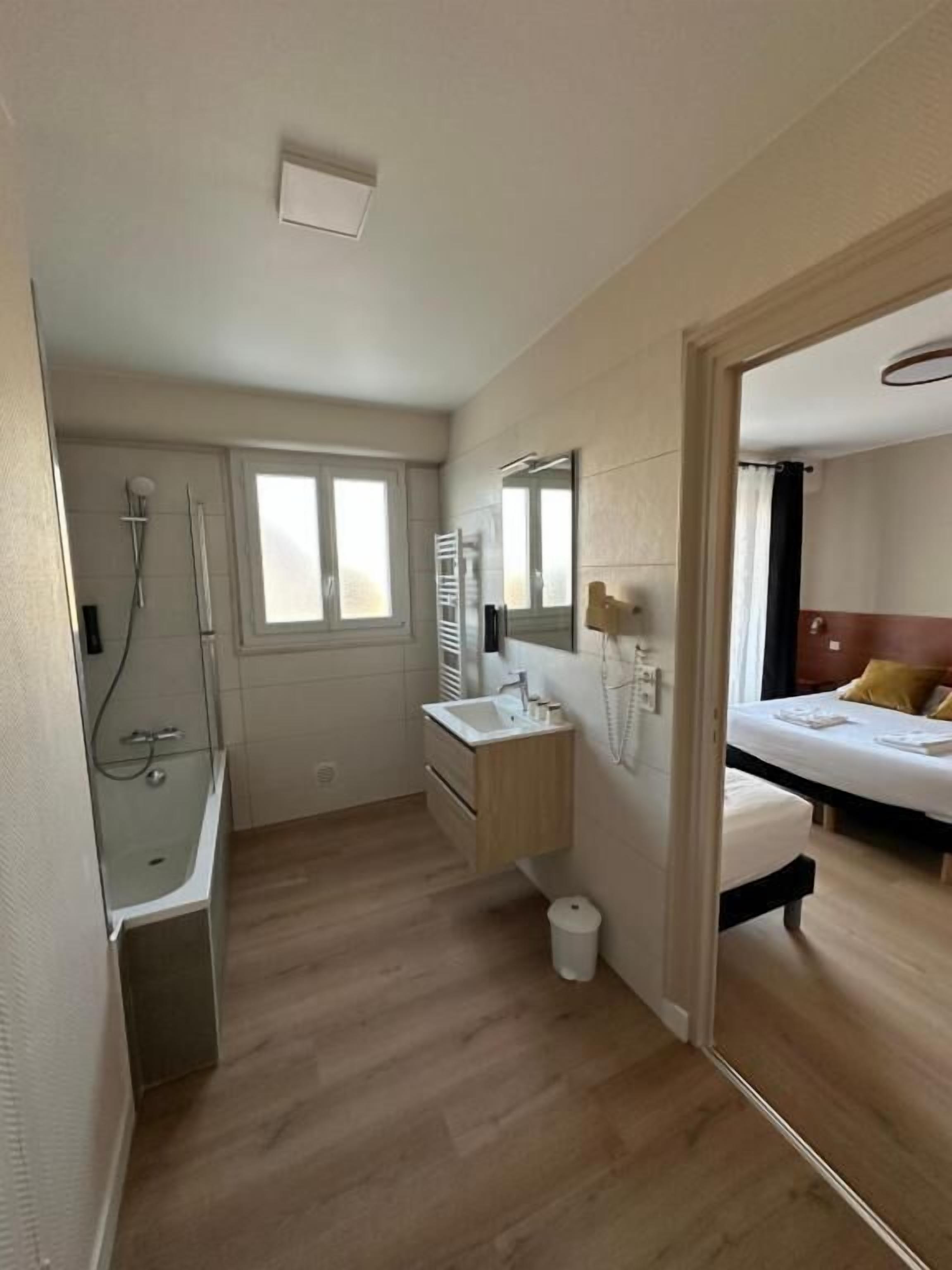 A hotel room with a shower, sink, and bed.