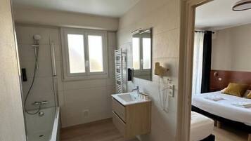 A hotel room with a shower, sink, and bed.