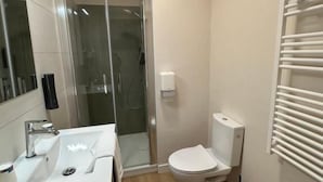 Un baño moderno con cabina de ducha de vidrio, inodoro blanco y tocador de madera.