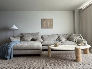 A living room with a sofa, a coffee table, a lamp, and a wall art piece. - Oceanfront Gem • Newly Renovated (Miami Beach)