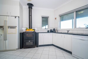 A modern kitchen with white cabinets, a black stove, a dishwasher, and a window with a view. - Gippsland Gem - 3/4 bedroom Accessible Accommodation (Yallourn North)