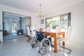 A spacious room with a dining table, wheelchair, and a view of the outdoors.