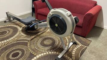 A stationary exercise bike with a 'concept' label, a red sofa, and a patterned rug.