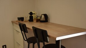 A kitchenette with a wooden countertop, two black chairs, a coffee maker, and a kettle. - Cozy Calade - Quiet, Self-Contained Studio with a Terrace - Downtown (Villefranche-sur-Saône)