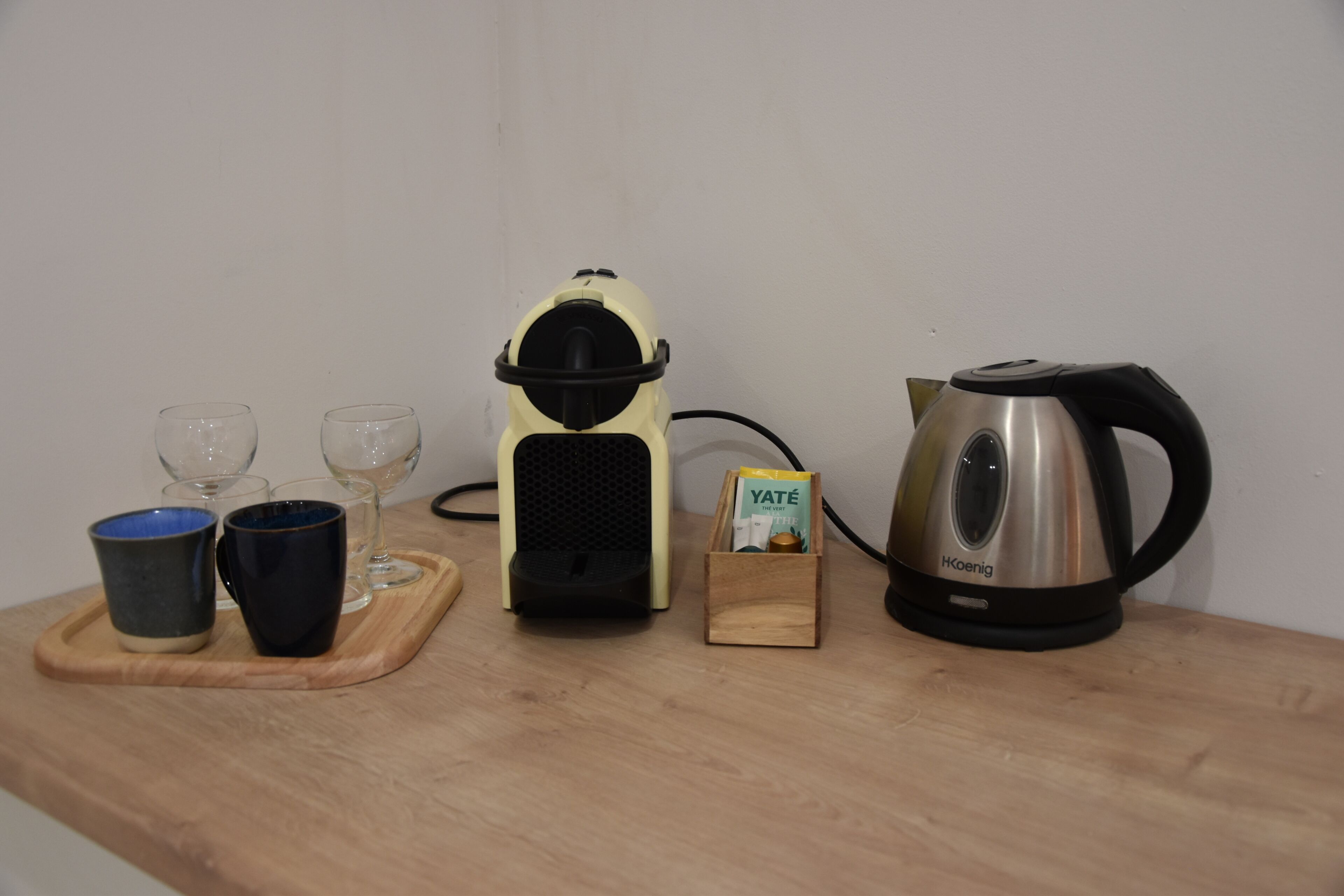 Eine Küchenarbeitsfläche mit Kaffeemaschine, Wasserkocher, zwei Tassen und einer kleinen Holzkiste.