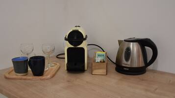 Eine Küchenarbeitsfläche mit Kaffeemaschine, Wasserkocher, zwei Tassen und einer kleinen Holzkiste.