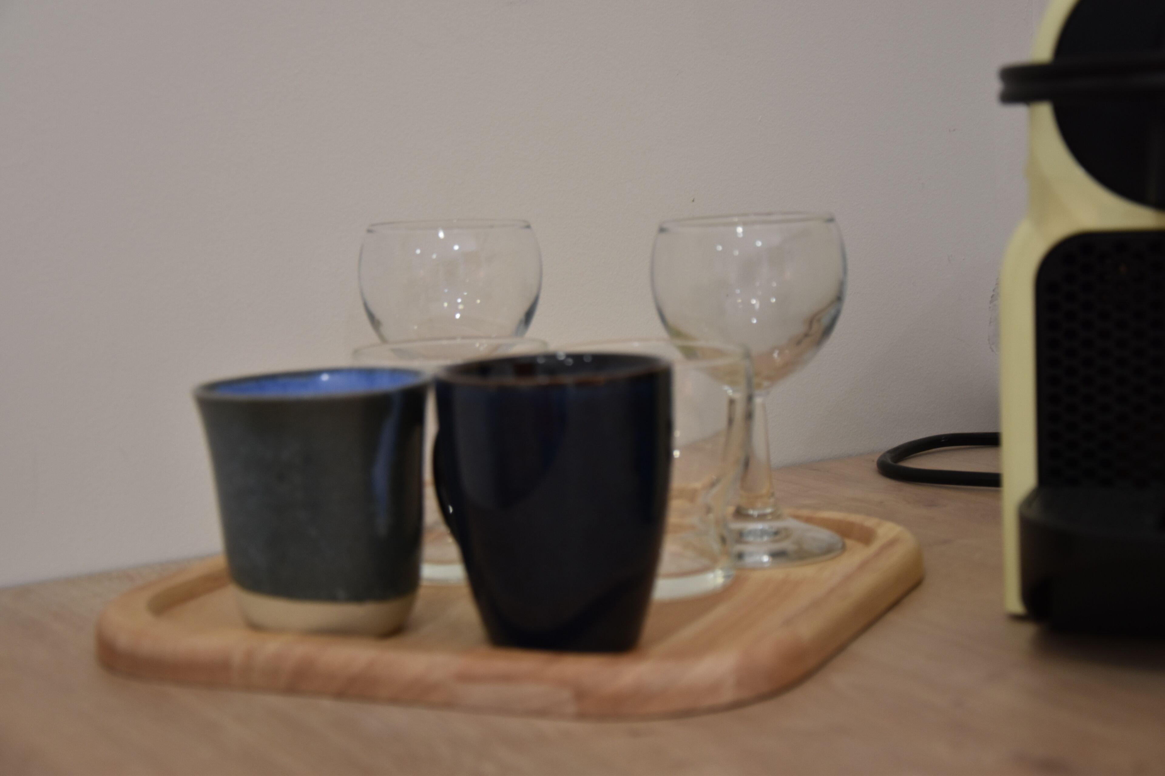 Un safata de fusta amb tres tasses i dues flautes sobre una taula.
