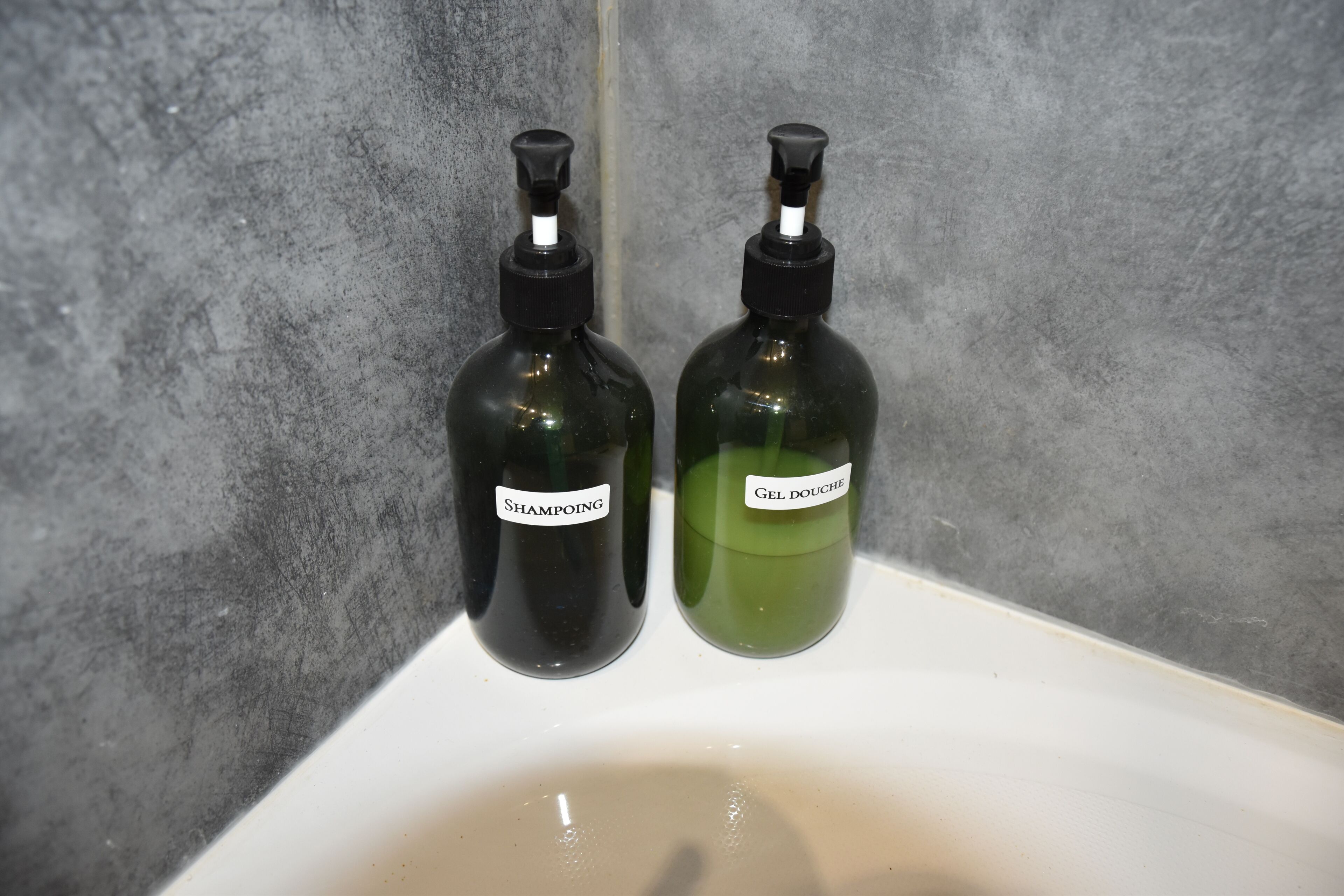 Dos botellas de champú y gel de ducha sobre un lavabo blanco.