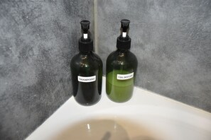 Dos botellas de champú y gel de ducha sobre un lavabo blanco.