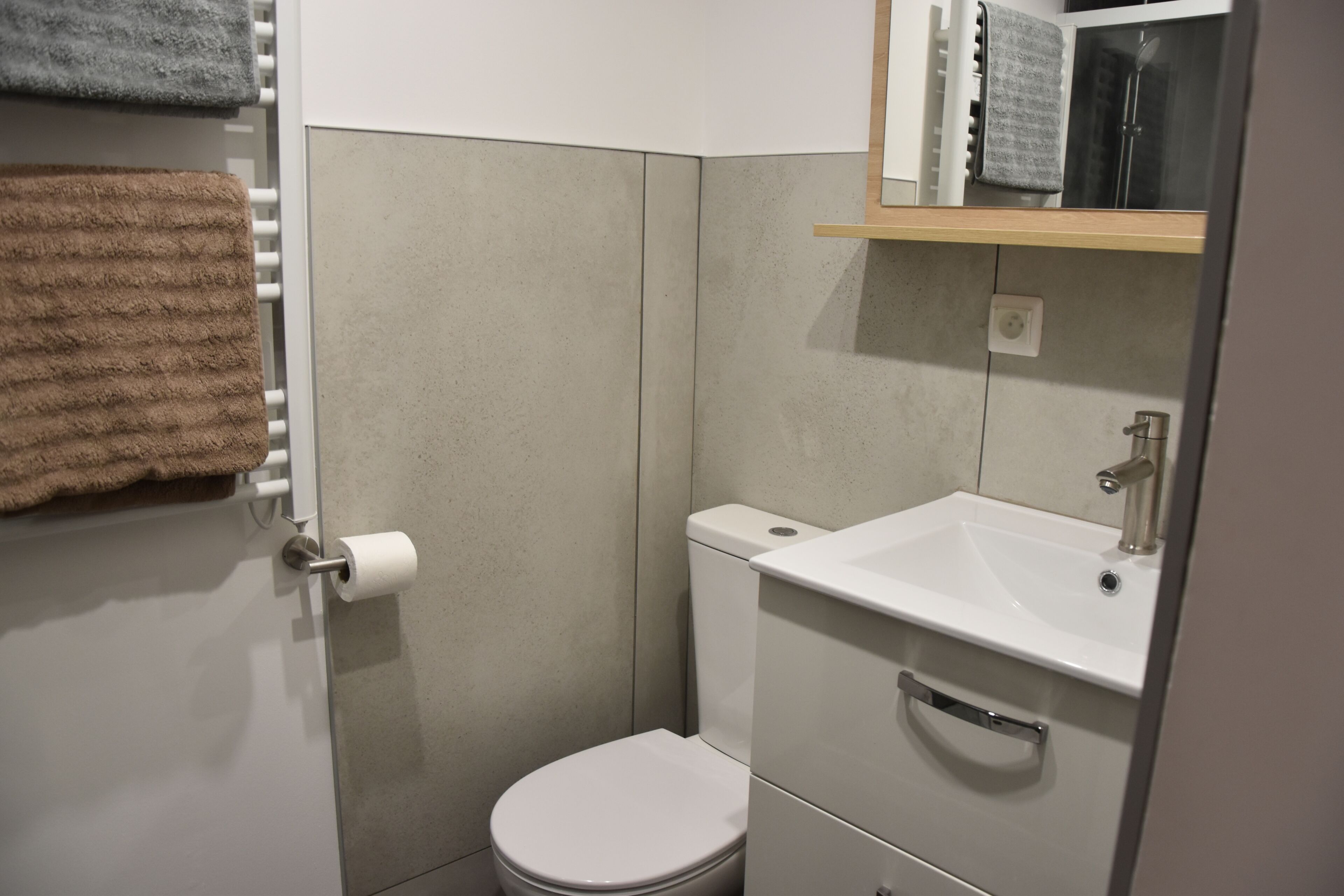 Un baño pequeño con inodoro, lavamanos y toallero.