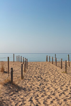 A sandy beach with wooden posts and ropes forming a barrier. - A charming little house nestled between vineyards and the sea. (Saifores)