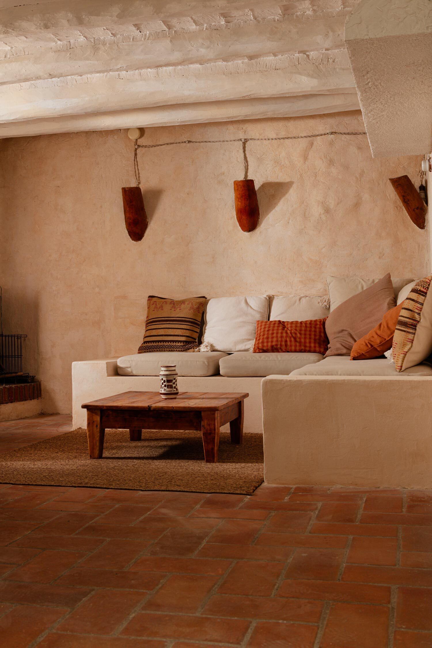 A cozy living room with a white sofa, a wooden coffee table, and a hanging light fixture.