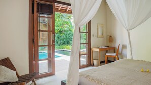 A bedroom with a bed, a chair, a desk, and a view of a swimming pool. - Villa Charlie Seminyak (Bali)