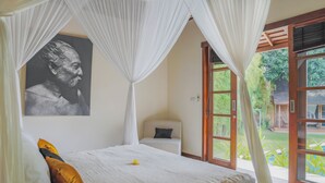 A bedroom with a bed, a bedside table, a chair, a window, and a door. - Villa Charlie Seminyak (Bali)