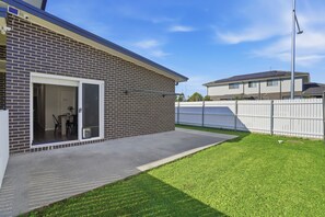 Ein modernes Haus mit Ziegelaußenwand, einer überdachten Terrasse und einem gepflegten Rasen.