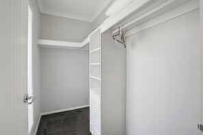Ein schmaler Flur mit einer weißen Tür, einem weißen Schrank mit Regalen und einer weißen Wand.