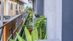 Un balcon agrémenté de plantes en pot, doté d’une rambarde en métal et offrant une vue sur les bâtiments voisins.