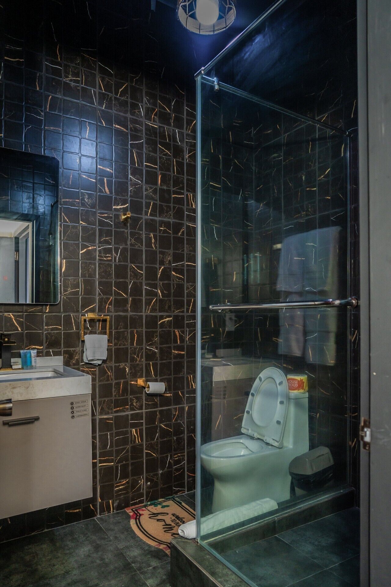 Une salle de bain avec une paroi de douche en verre, des toilettes, un lavabo et un miroir.