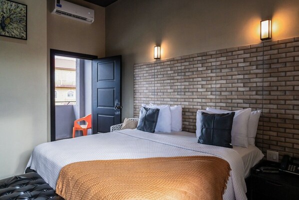 A hotel room with a bed, a brick-patterned headboard, a door, and a window.
