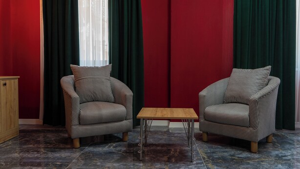 Dos sillones a cuadros de pied de pavo, una mesa de centro de madera y un suelo de mármol.