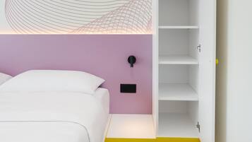 Un dormitorio moderno con una cama blanca, una pared de acento rosa y un suelo con estampado geométrico.